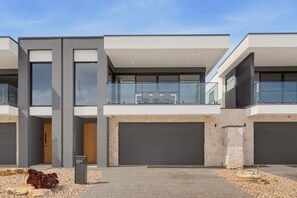 A modern residential building with a flat roof, large windows, and a stone facade. - Oceanfront 4-Bed Home Surf & Serenity (Seaford)