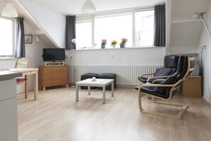 Een moderne woonkamer met een televisie, een eettafel, een bank en een fauteuil.