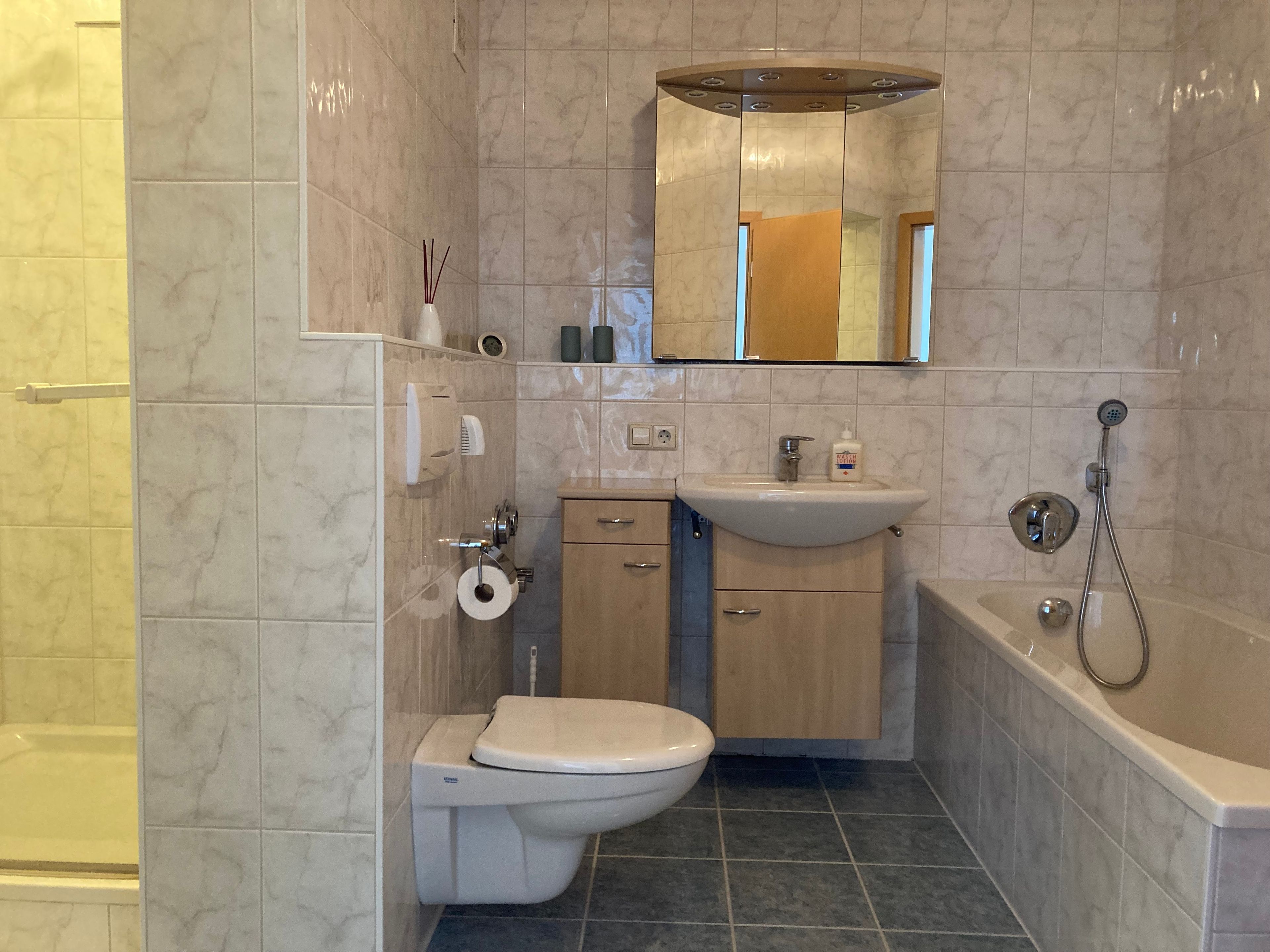 Ein Badezimmer mit Toilette, Waschbecken, Spiegel und Dusche.