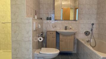Ein Badezimmer mit Toilette, Waschbecken, Spiegel und Dusche.