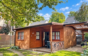 Une cabane en bois dotée d’une véranda, d’un coin repas et d’un espace extérieur couvert.