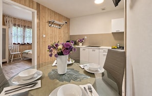 A modern kitchen with a dining table set for two, a vase of flowers, and a wooden wall. - Pet friendly home in Pobierowo with WiFi (Pobierowo)