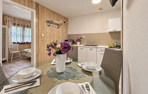Une cuisine moderne avec une table à manger pour deux personnes, un vase de fleurs et un mur en bois.