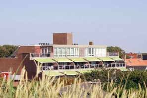 A multi-story building with a flat roof, large windows, and a green awning over the entrance. - Residence de l'Europe / Noordstraat 19D (Domburg)