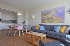 Ein zeitgemäßer Wohnraum mit Essbereich, einer Sofagarnitur und einem großen Gemälde.