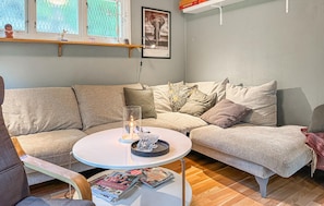 Ein gemütliches Wohnzimmer mit einem Ecksofa, einem runden Couchtisch und einem Bücherregal.