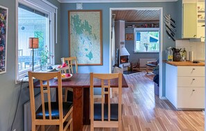 Ein Essbereich mit Holztisch und -stühlen, einer Karte an der Wand und einer Küche mit Schränken und Kochutensilien.