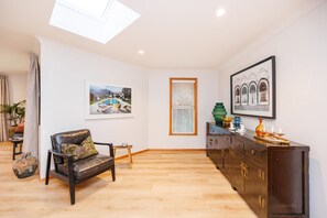 A spacious room with a wooden floor, a leather sofa, a sideboard, and a skylight. - Hokowhitu Haven | Style, Space & Luxury (Palmerston North)