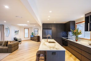 A modern kitchen with a marble countertop, dark cabinetry, and a built-in oven. - Hokowhitu Haven | Style, Space & Luxury (Palmerston North)