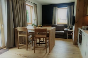 A dining area with a table and chairs, a sofa, and a kitchen area with cabinets and a countertop. - Gapphof (Granny&Gala) (Algund)