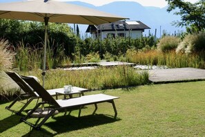 A patio with a table and chairs, a large umbrella, and a view of a mountain and a house in the background. - Gapphof (Granny&Gala) (Algund)