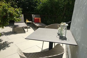 An outdoor patio area with a table, chairs, and a small table with a bottle. - Gapphof (Granny&Gala) (Algund)
