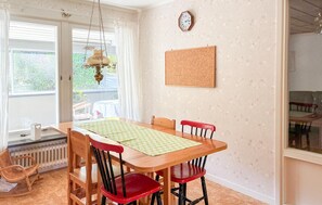 A dining area with a wooden table, four chairs, a corkboard on the wall, a clock, and a radiator. - 3 bedroom pet friendly home in Stugun (Stugun)