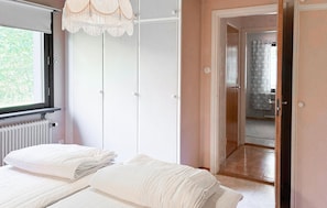 Ein Schlafzimmer mit Bett, Kleiderschrank, Heizkörper und einer Tür zu einem Badezimmer.