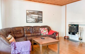 A living room with a brown leather sofa, a wooden coffee table, and a fireplace. - 3 bedroom pet friendly home in Stugun (Stugun)