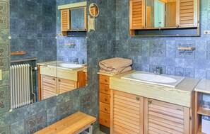 Ein Badezimmer mit zwei Waschbecken, Holzschränken, einem Spiegel und einem Handtuch auf der Ablagefläche.