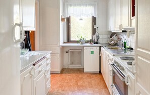 A kitchen with white cabinetry, a built-in oven, a dishwasher, and a window with a plant on the windowsill. - 3 bedroom pet friendly home in Stugun (Stugun)