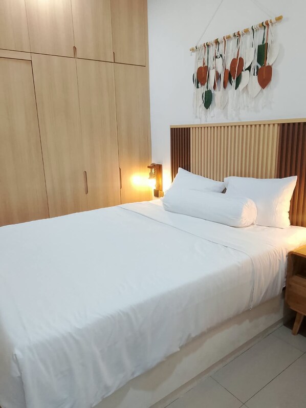 A bedroom with a large bed, wooden wardrobe, and a wall-mounted decoration. - Commonstay Co-Living Denpasar (Denpasar)