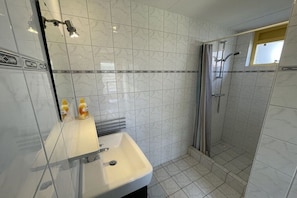 A bathroom with a sink, mirror, and shower. - Holiday home with 1 bedroom (Julianadorp)
