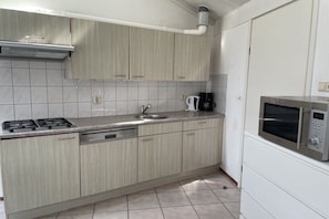 Een keuken met een gasfornuis, spoelbak en een magnetron.