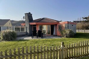 Een huis met pannendak, schoorsteen en omheinde tuin.