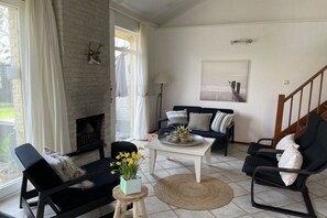 Ein Wohnzimmer mit Kamin, einer Couch, einem Couchtisch und einem Sessel.