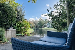 A garden with a pond, a wooden structure, and a chair. - Holiday home Duynopgangh 27 (Julianadorp)