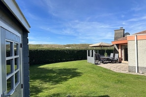 Une pelouse bien entretenue avec un espace patio, une table à manger et des chaises.