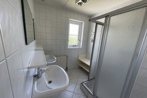 Une salle de bain équipée d’un lavabo, d’un miroir, d’une fenêtre et d’un espace douche.