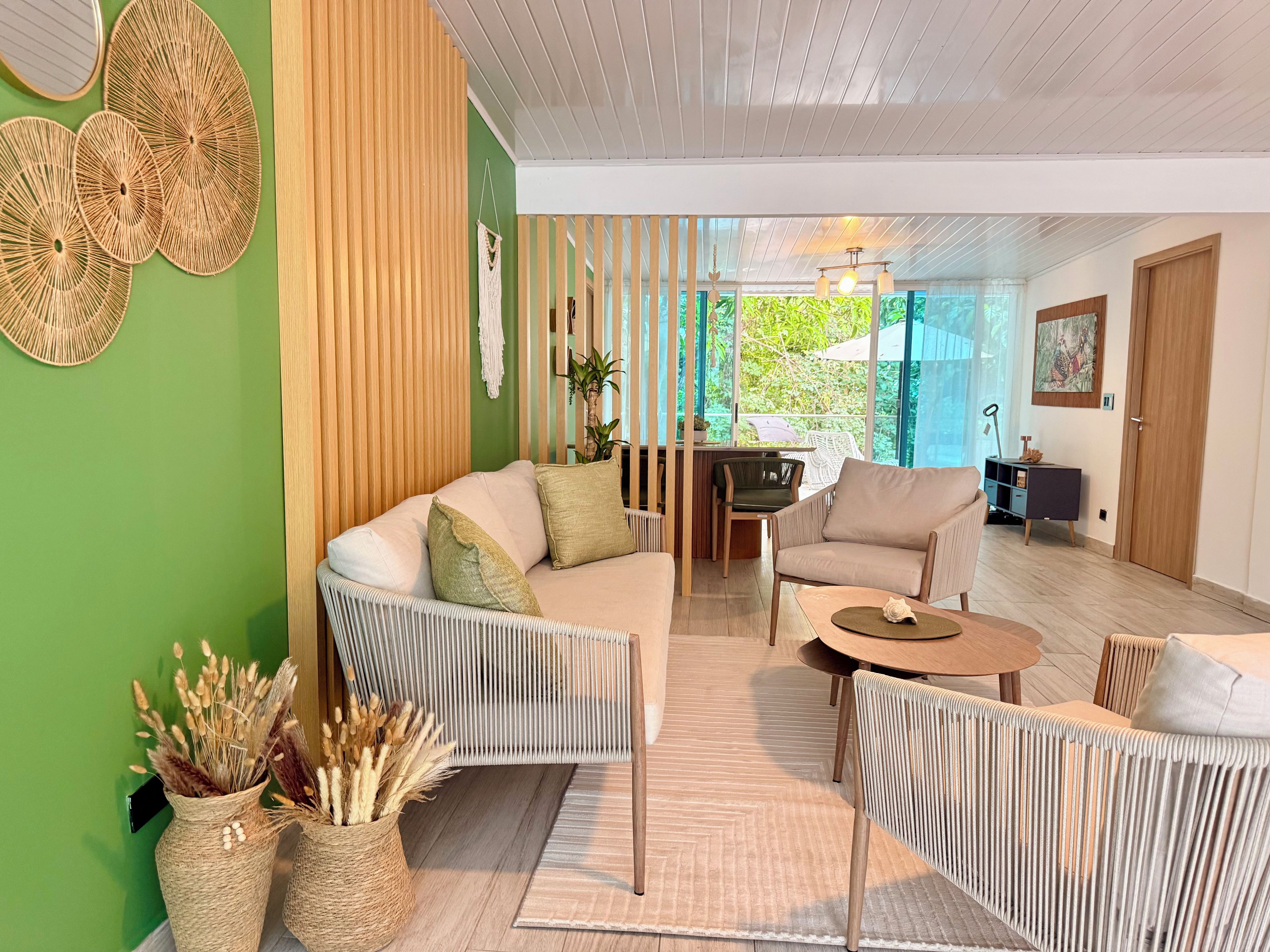 A modern living room with a sofa, armchairs, a coffee table, and a dining area.