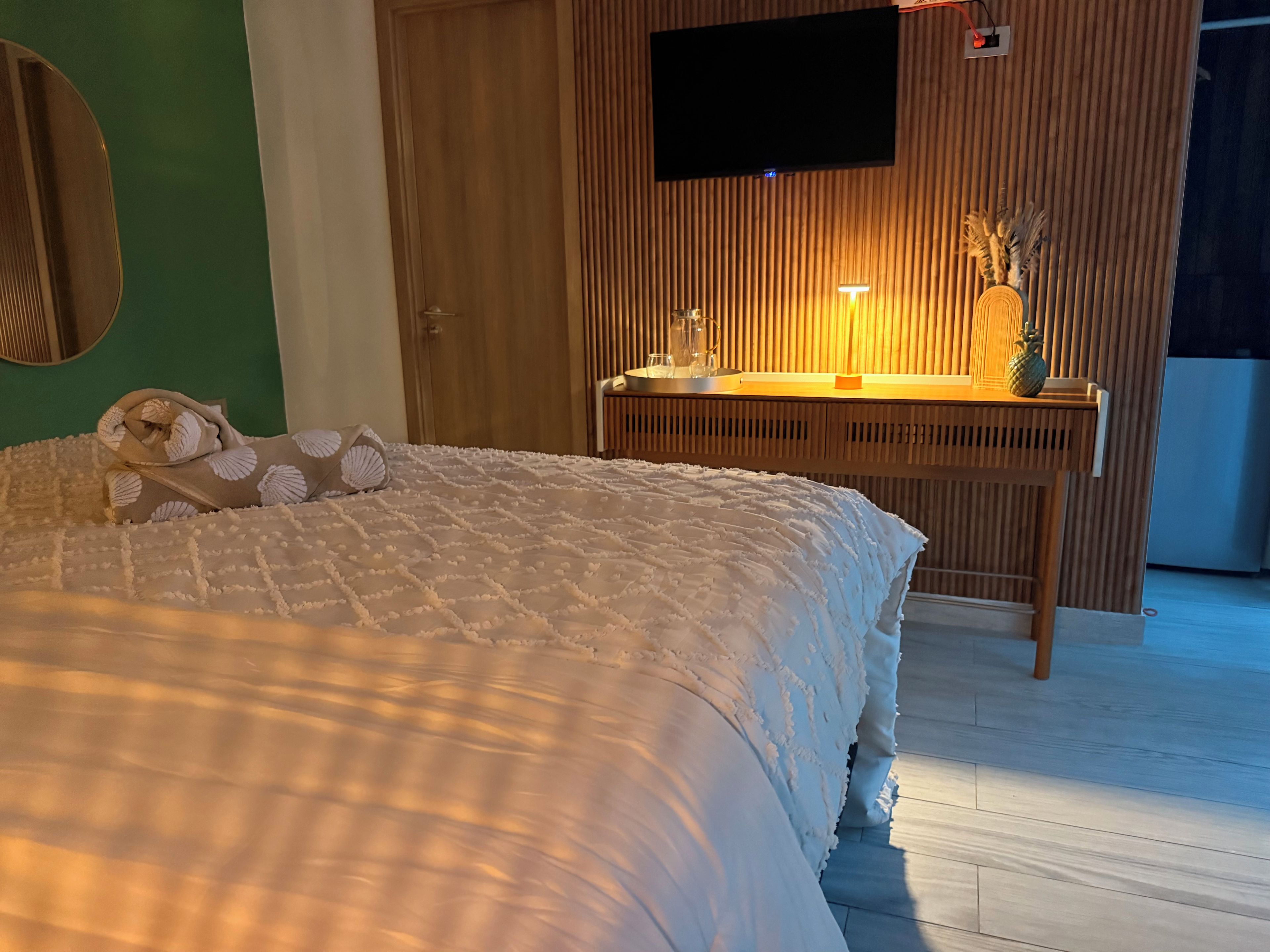 Ein Schlafzimmer mit einem Bett, einem Holztisch, einem Fernseher und einer Wandleuchte.