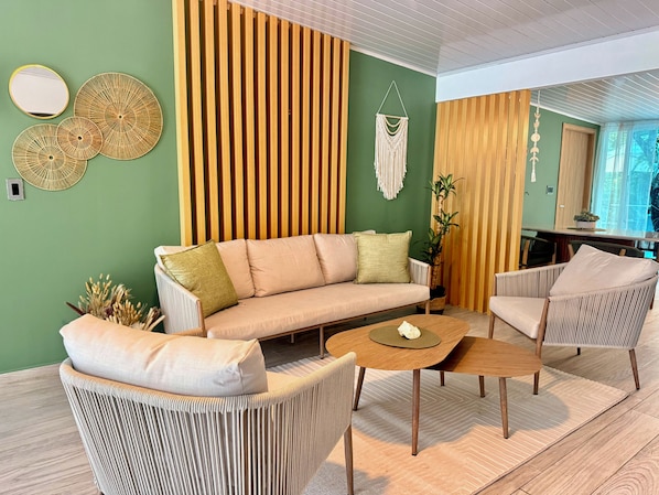 A modern living room with a sofa, two armchairs, a coffee table, and a decorative wall panel.