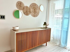 Un interior moderno con una consola de madera, arte decorativo en la pared y un jarrón con flores secas.