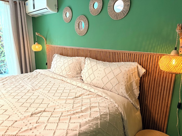 A bed with a quilted cover, a wooden headboard, and wall-mounted mirrors.