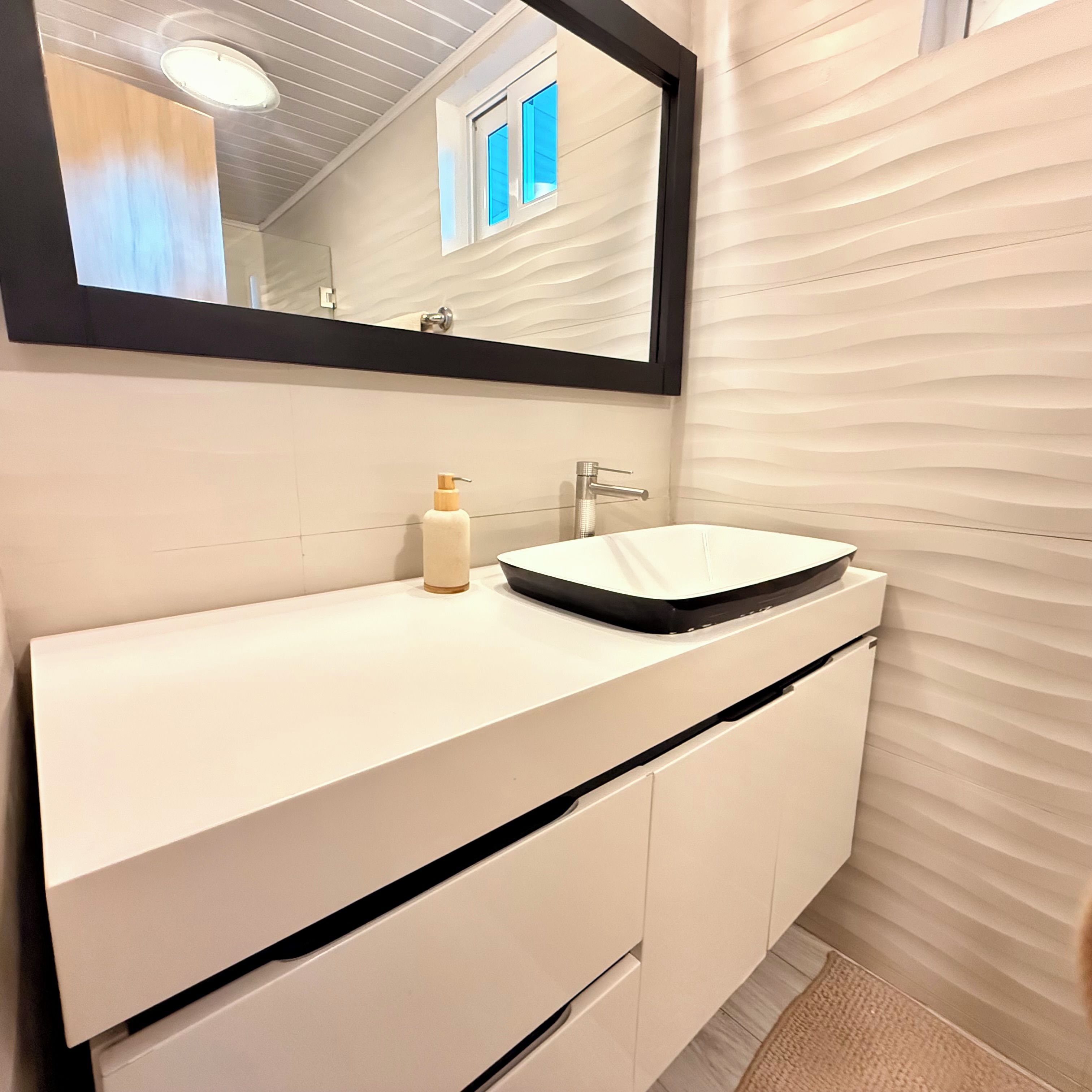 A bathroom with a white vanity, a mirror, and a sink.