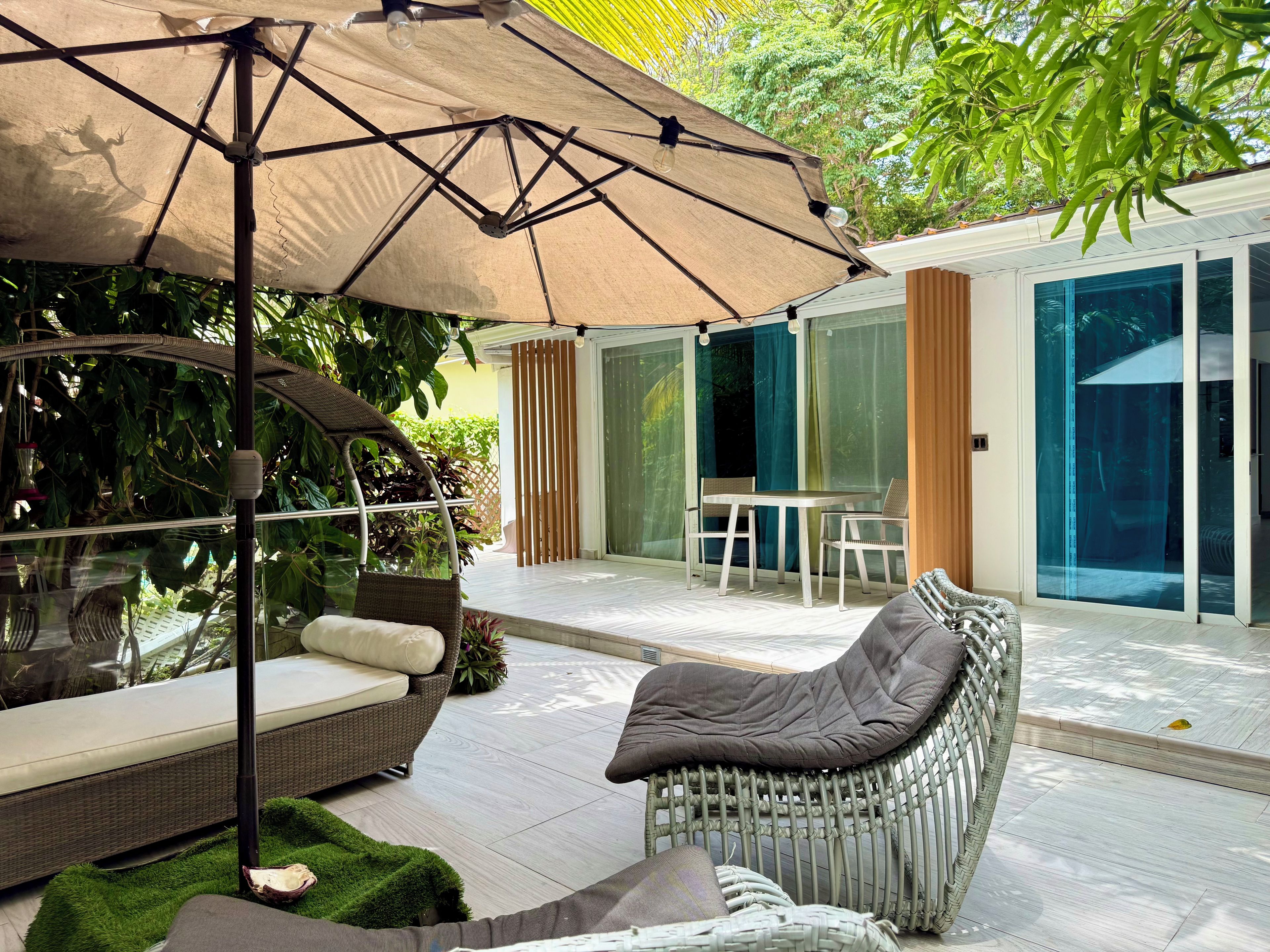 Une terrasse extérieure moderne, avec un fauteuil en osier, une table et un grand parasol.