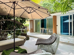 A modern outdoor patio with a wicker chair, a table, and a large umbrella.