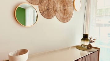 A wall with three circular wall decorations, a round mirror, and a vase with dried flowers on a white console table.
