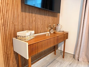 A wooden console table with a television mounted above it, a wicker basket, and a glass pitcher on the table.