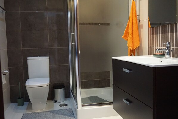A modern bathroom with a toilet, a shower, and a sink.