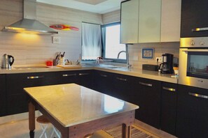 A modern kitchen with a central island, stainless steel appliances, and a window providing natural light.