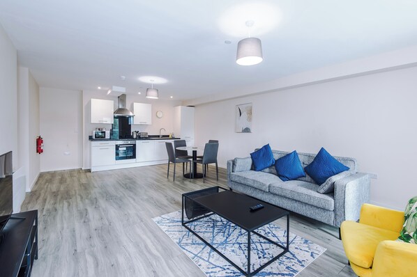 A modern living room with a grey sofa, a black coffee table, and a yellow armchair. - Spacious 2BDR with Modern Comfort Sleeps 4 (Manchester)