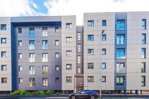 A modern multi-story residential building with a mix of window styles and balconies. - Spacious 2BDR with Modern Comfort Sleeps 4 (Manchester)