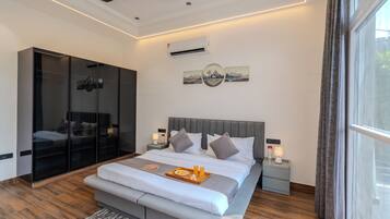A modern bedroom with a large bed, bedside lamps, a ceiling fan, and a view of the outdoors through a window.