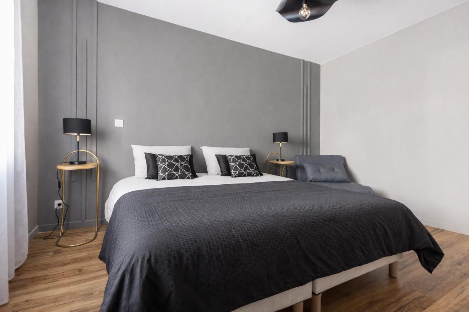 A modern bedroom with a large bed, two bedside tables, and a ceiling light fixture.