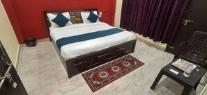 Habitació d'hotel amb un llit, una taula petita amb una ampolla i una cadira.