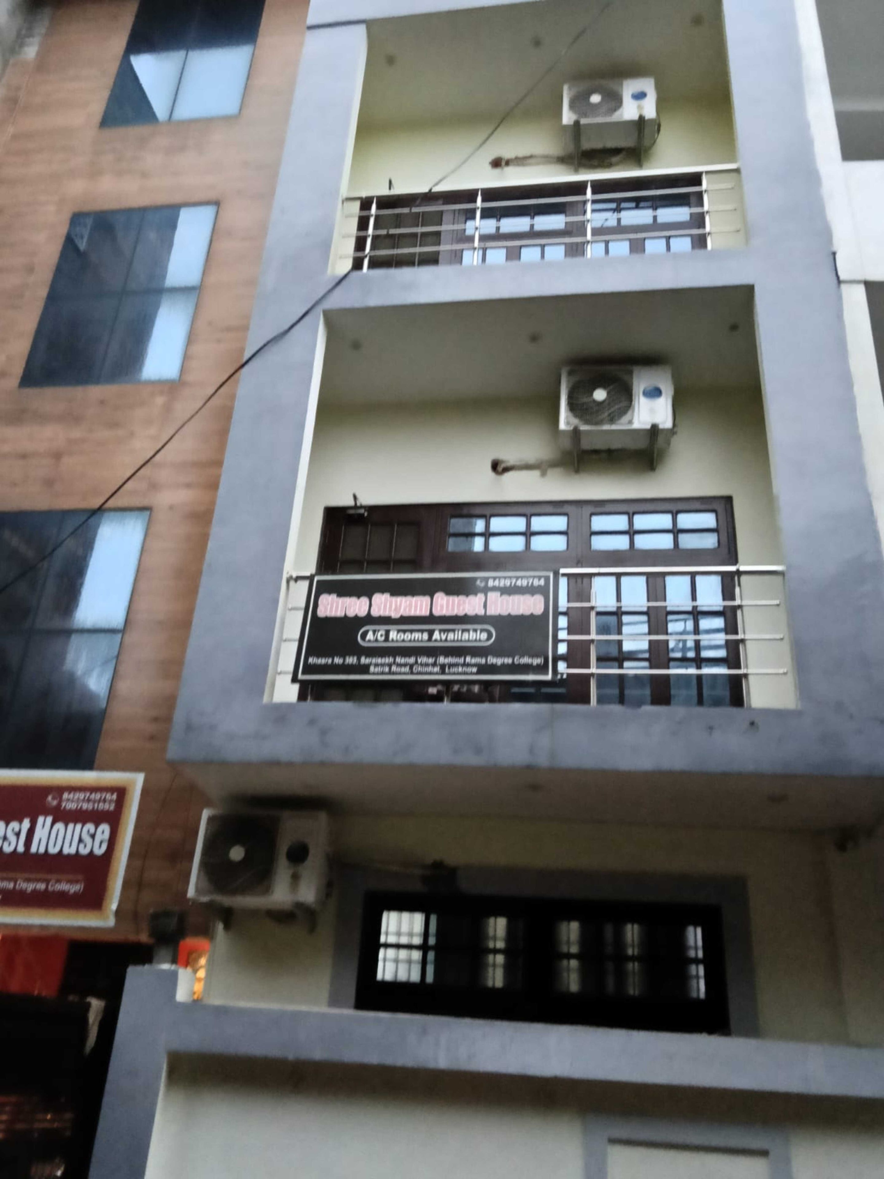 A multi-story building with balconies, air conditioning units, and a sign indicating A/C rooms are available.