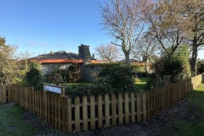 Een woonhuis met omheinde tuin, schoorsteen en een bord dat aangeeft dat het een privé woning is.