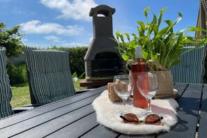 A patio with a stone oven, outdoor seating, and a bottle of rosé wine. - Beach Parcel 207 in the Strandslag holiday park (Julianadorp)
