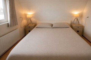 Une chambre à coucher avec un lit simple, deux tables de chevet et des lampes.